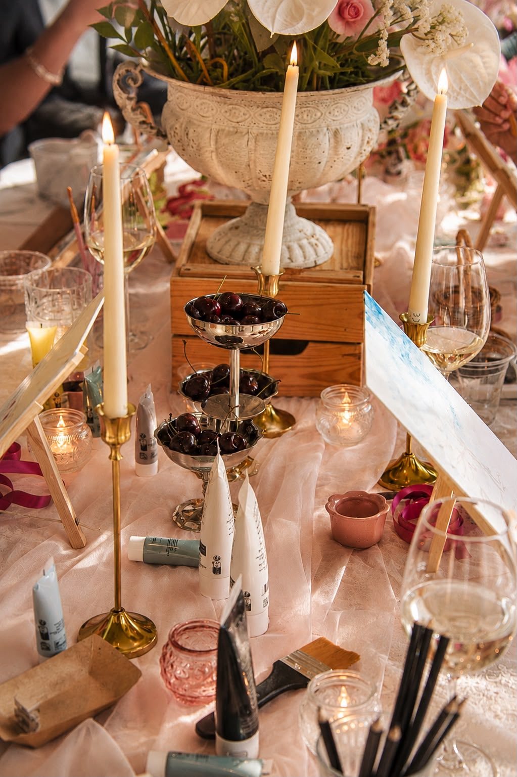 Table detail with candles and paint supplies, from a past Three Petals event