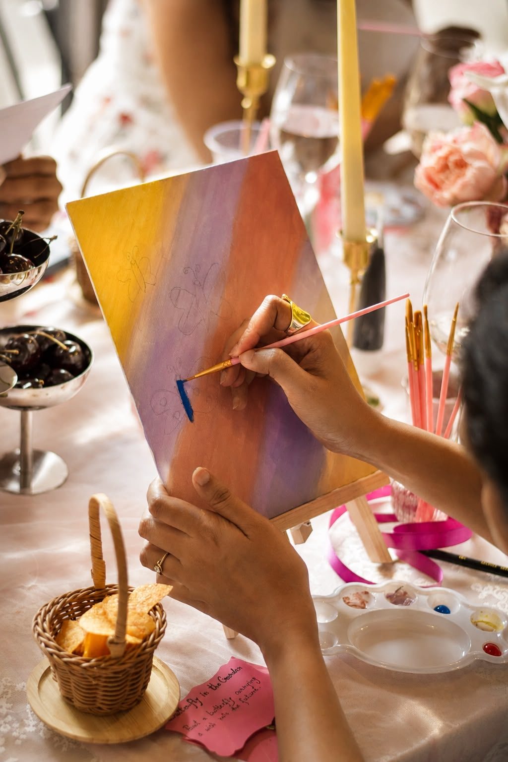Guest painting a butterfly canvas, from a past Three Petals event